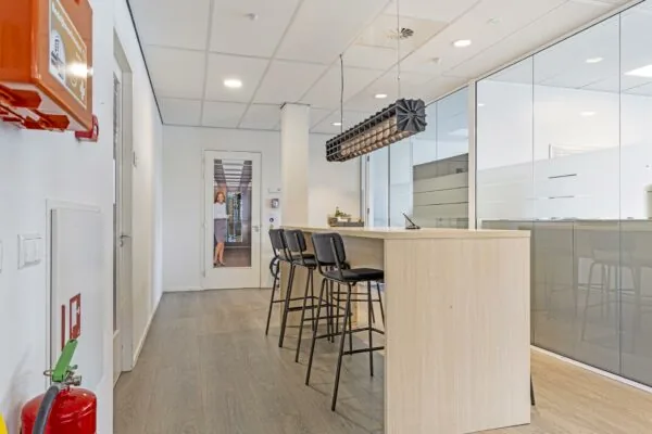 Moderne kantoorruimte aan de Fascinatio Boulevard met een hoge tafel, barkrukken en glazen vergaderruimtes.